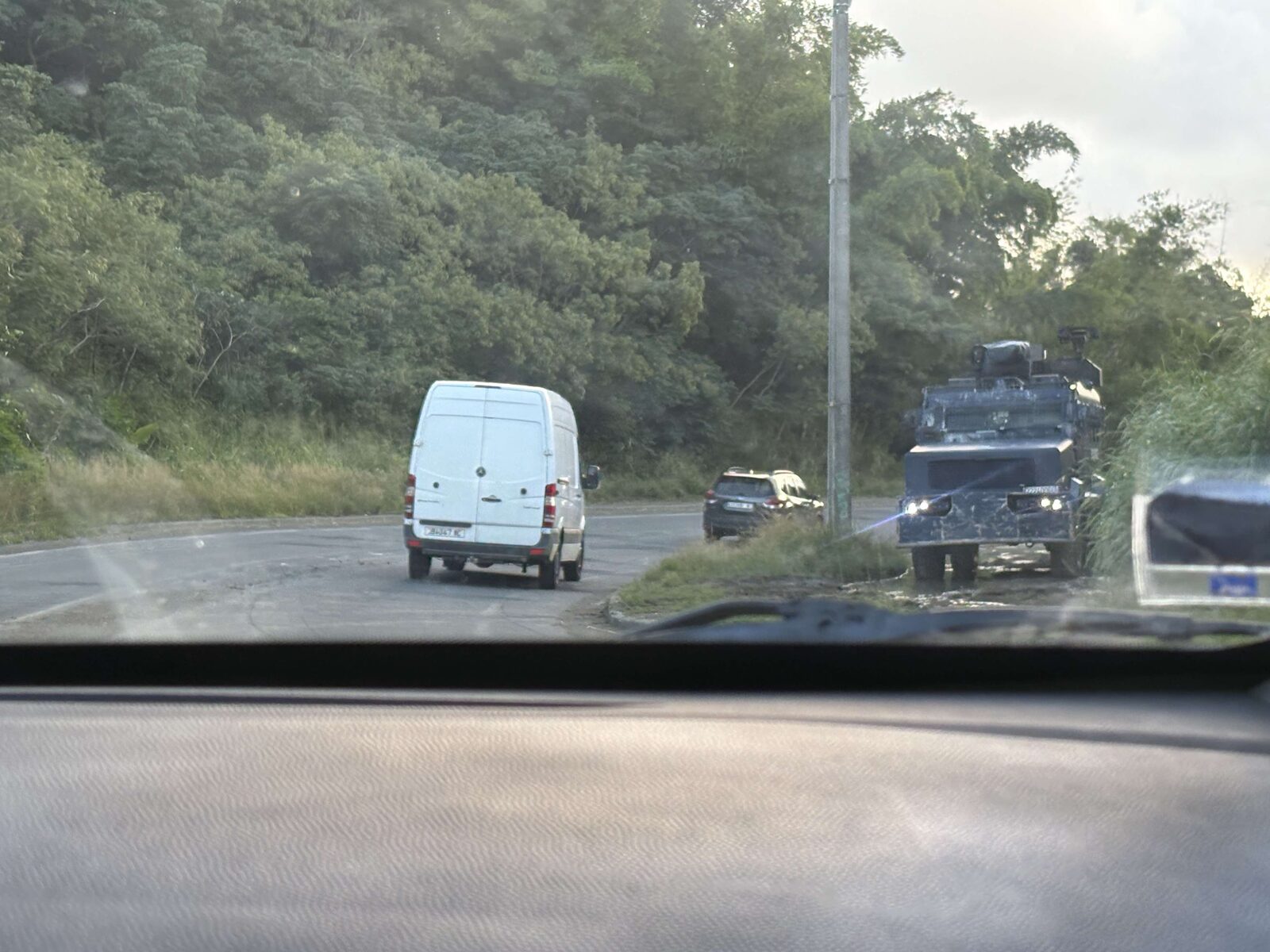 An armored police vehicle parked beside the road, seen from a passing car
