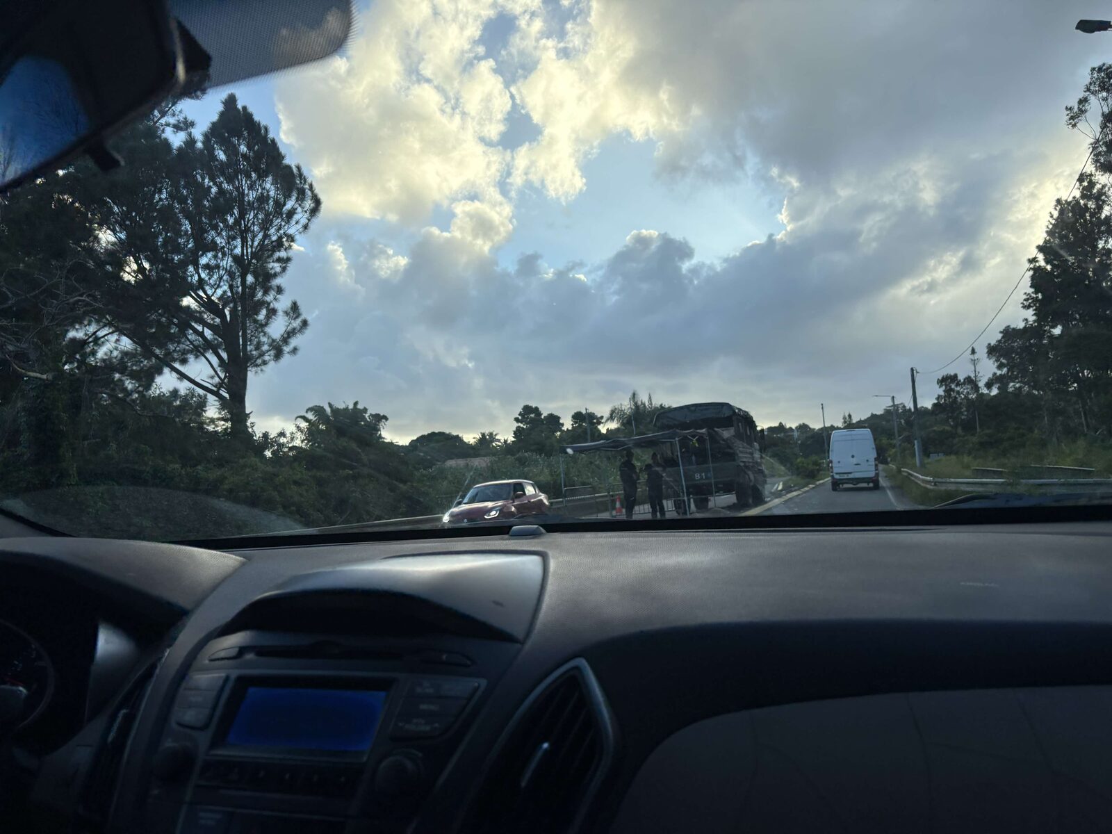 A roadside checkpoint with a military truck and officers stopping traffic