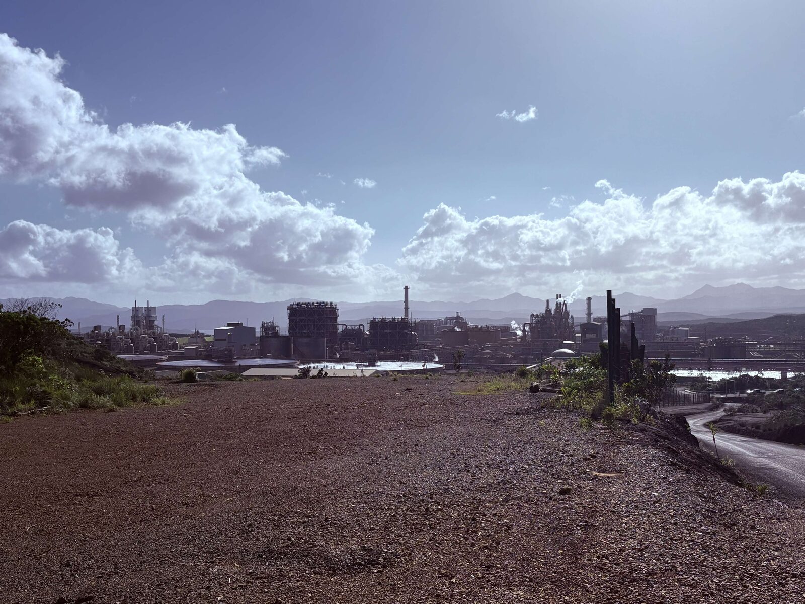 A large nickel processing plant on the coast, with mountains behind it